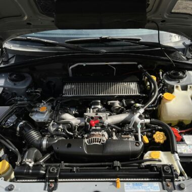 Close-up view of car engine with visible components under the open hood.